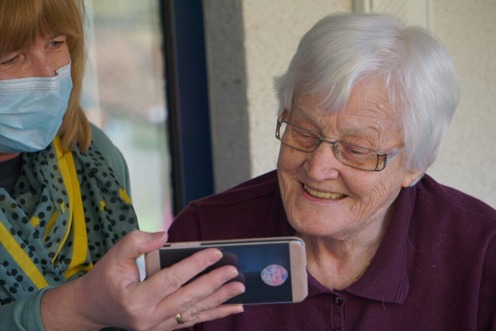 Old woman holding mobile phone, recalling family history.